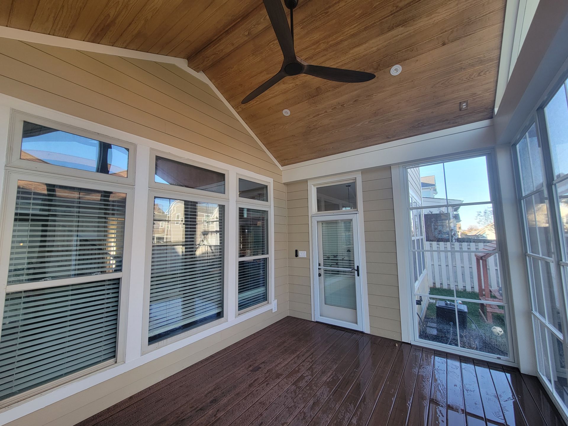 Empty sunroom with wood ceiling, ceiling fan, windows, and screened side walls.