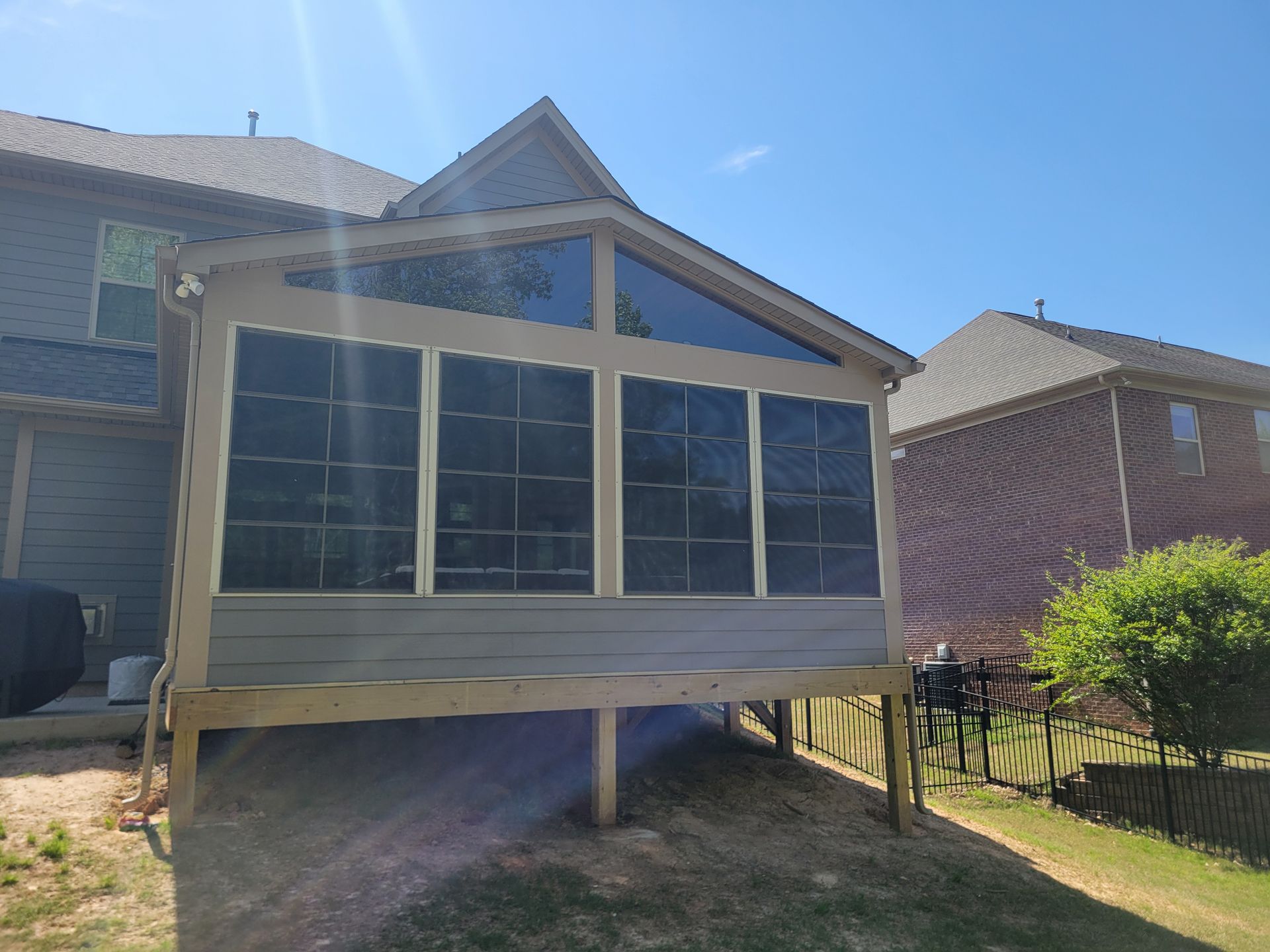 Screened porch addition with blue-gray siding and large windows in a backyard