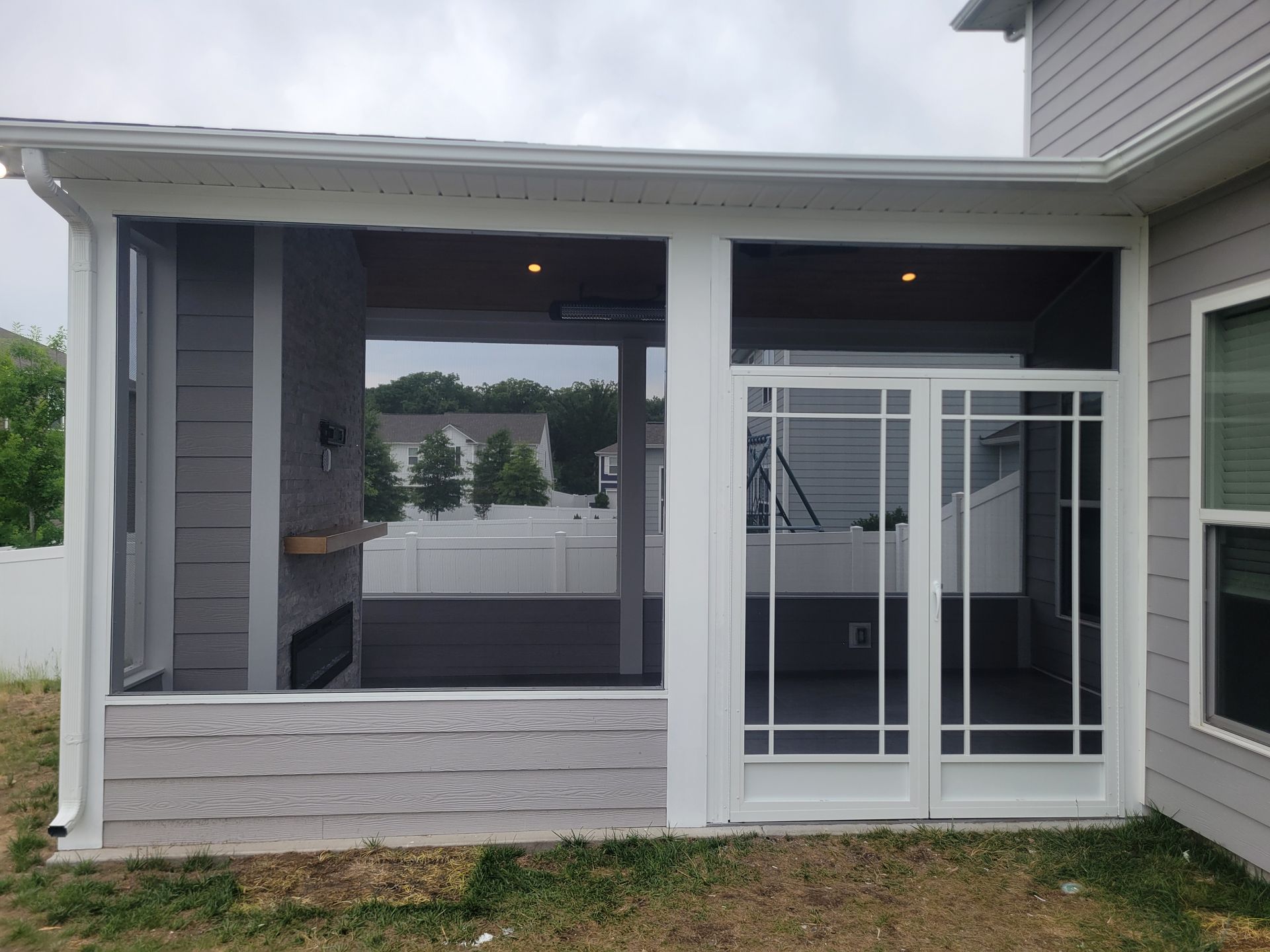 Covered patio with large screened opening and sliding glass door on a gray house