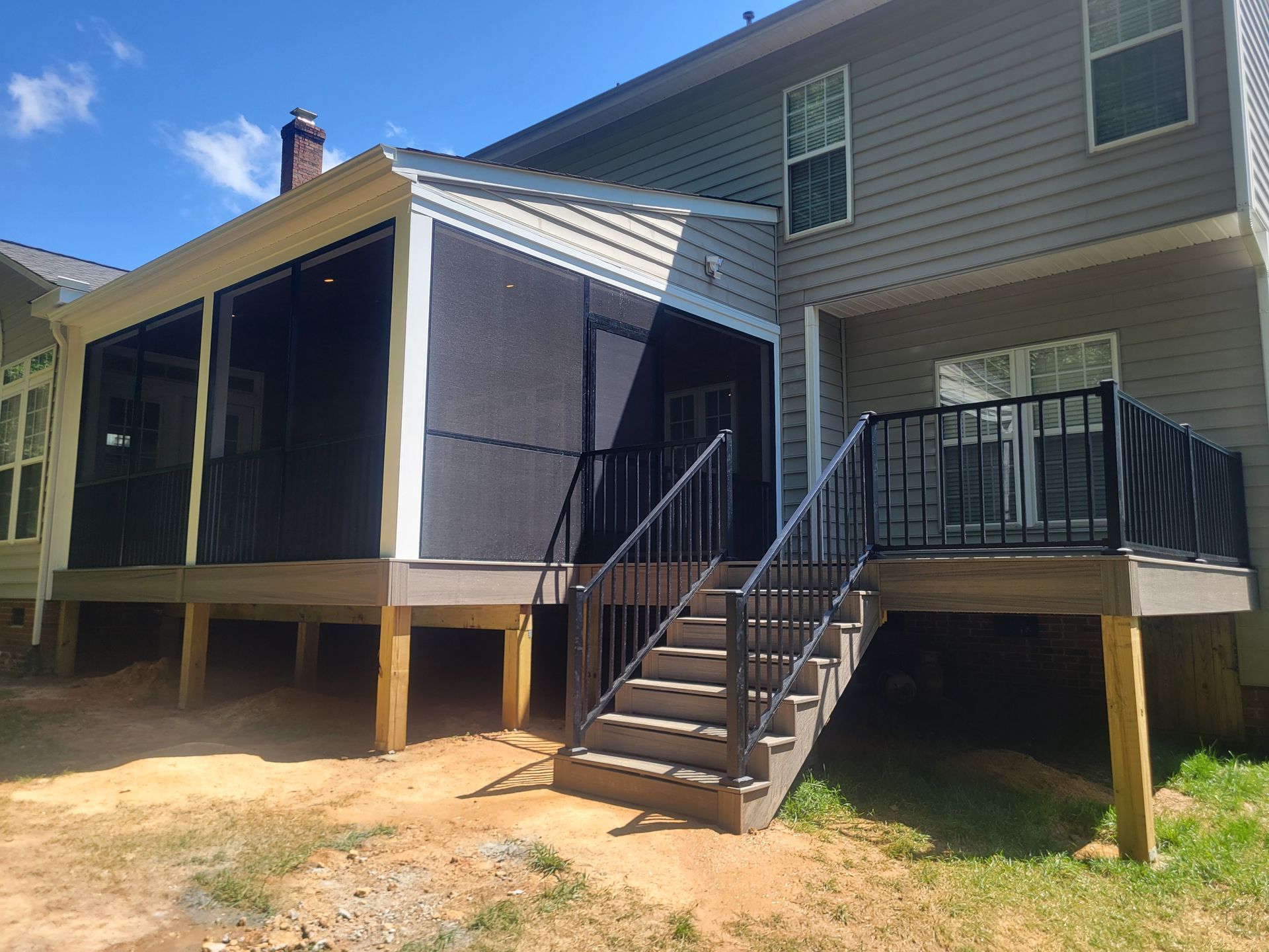 House exterior with raised screened porch, front steps, and small deck in a sunny yard