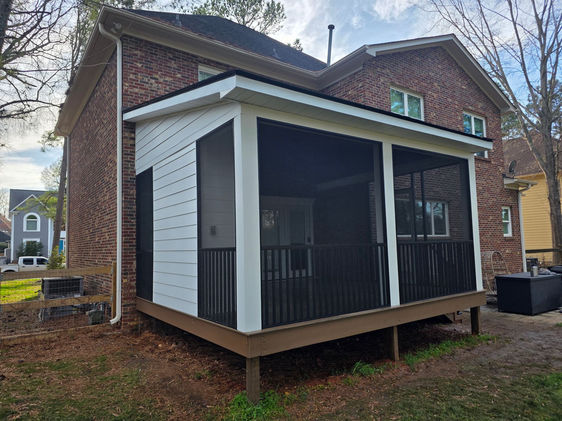 Newly built screened porch on a brick house, with white trim and black railings