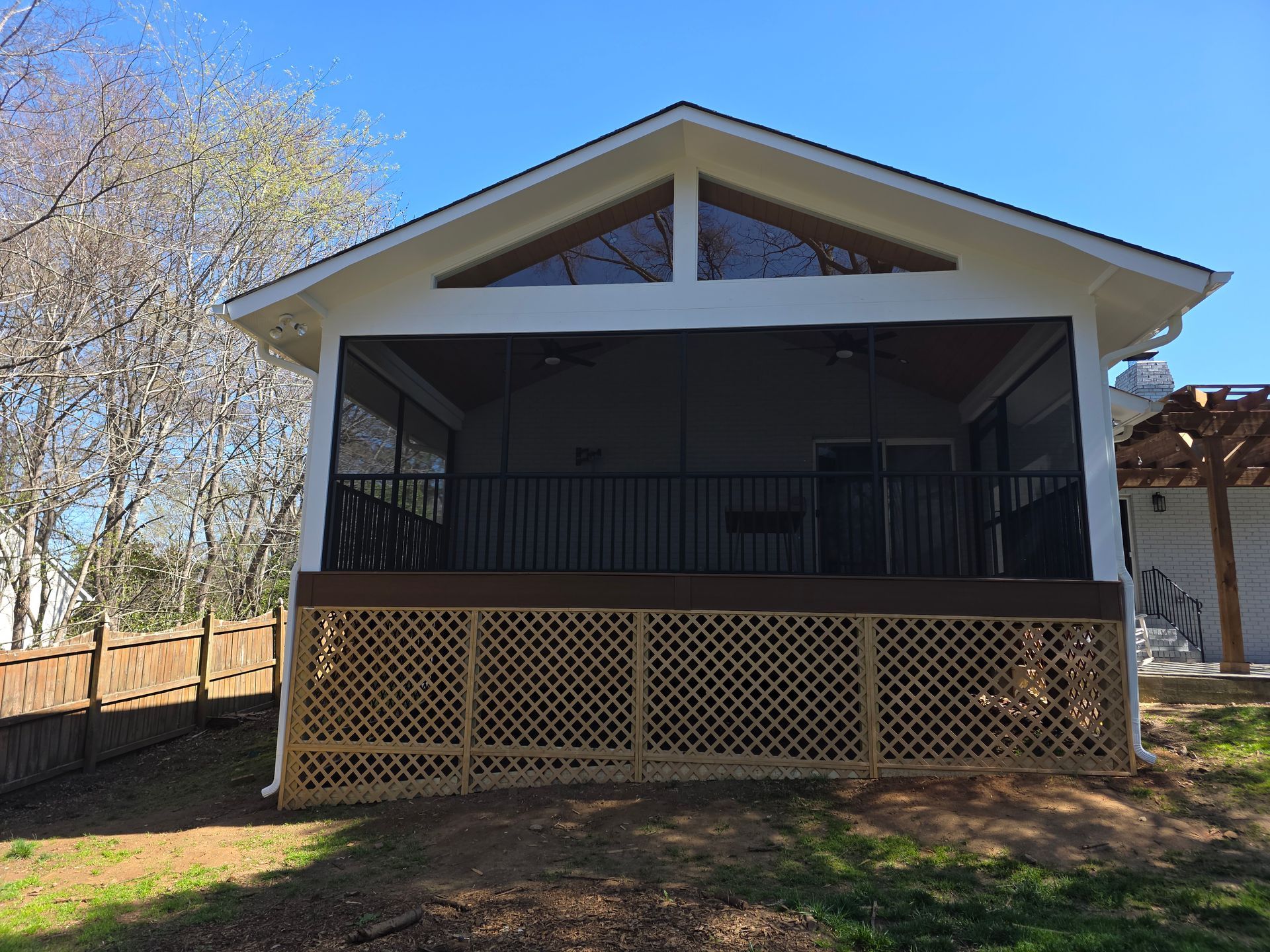 Screened porch with lattice skirting on a small house in a sunny yard