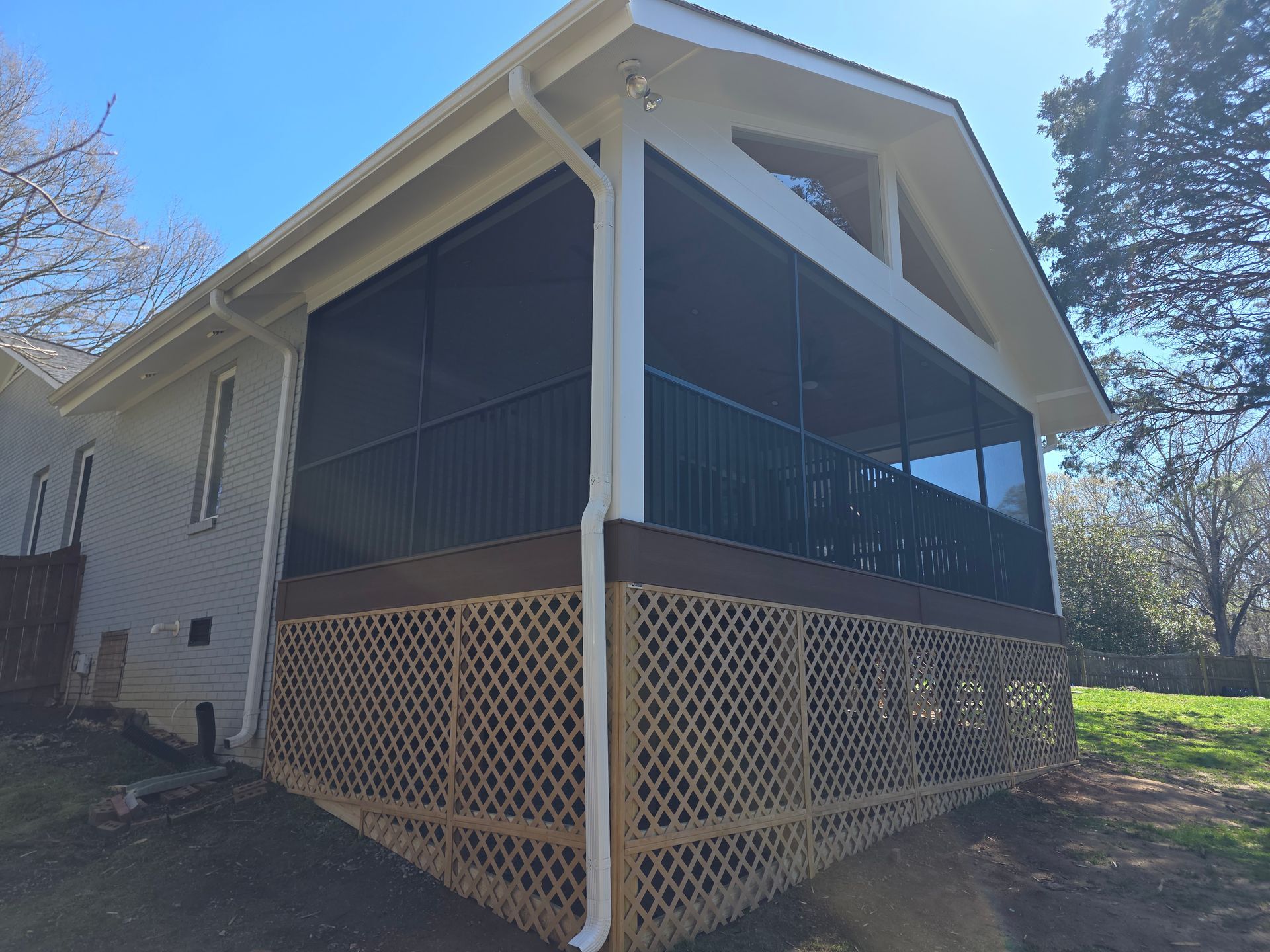 House with screened porch and lattice foundation on a sunny hillside