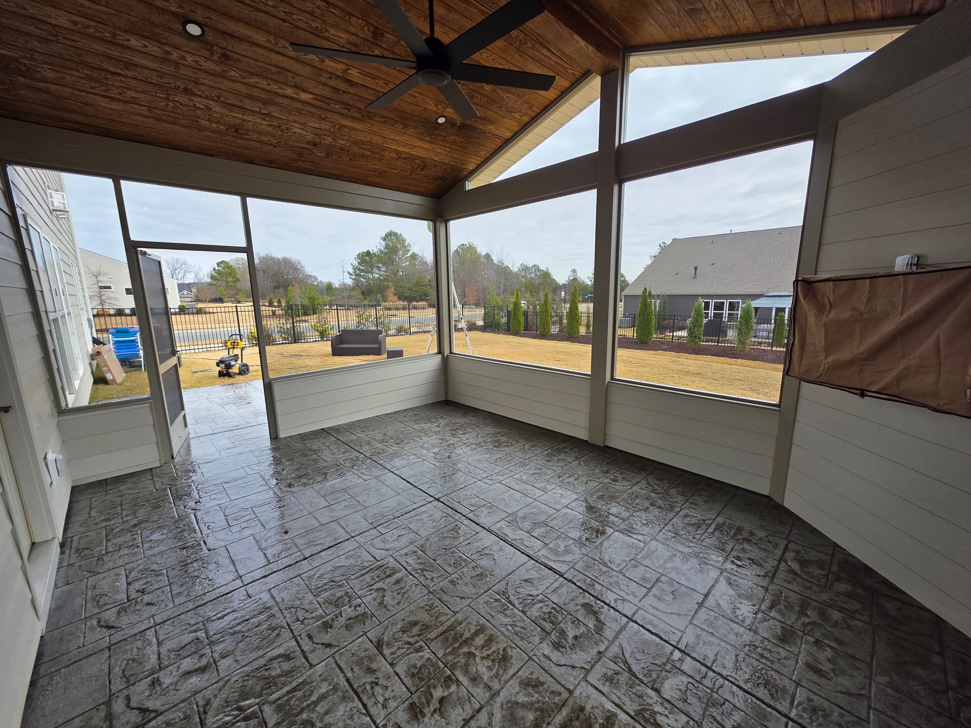 Covered porch with tiled floor, wooden ceiling, and open views of a residential neighborhood.