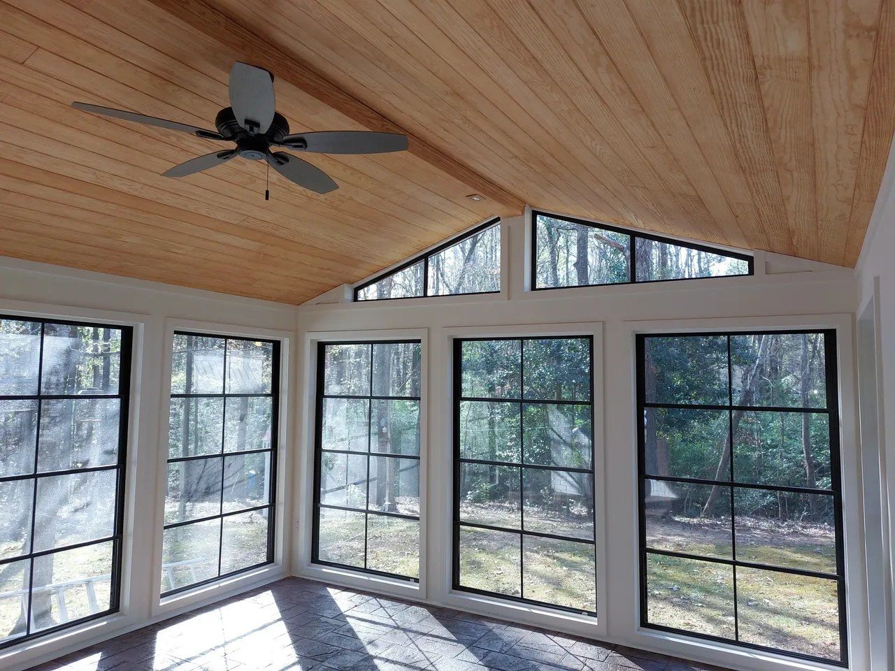 A room with a lot of windows and a ceiling fan