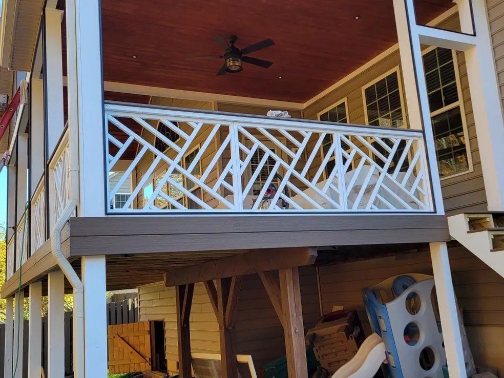 Covered porch with white lattice railing, wood ceiling, and a climbing wall in the yard below
