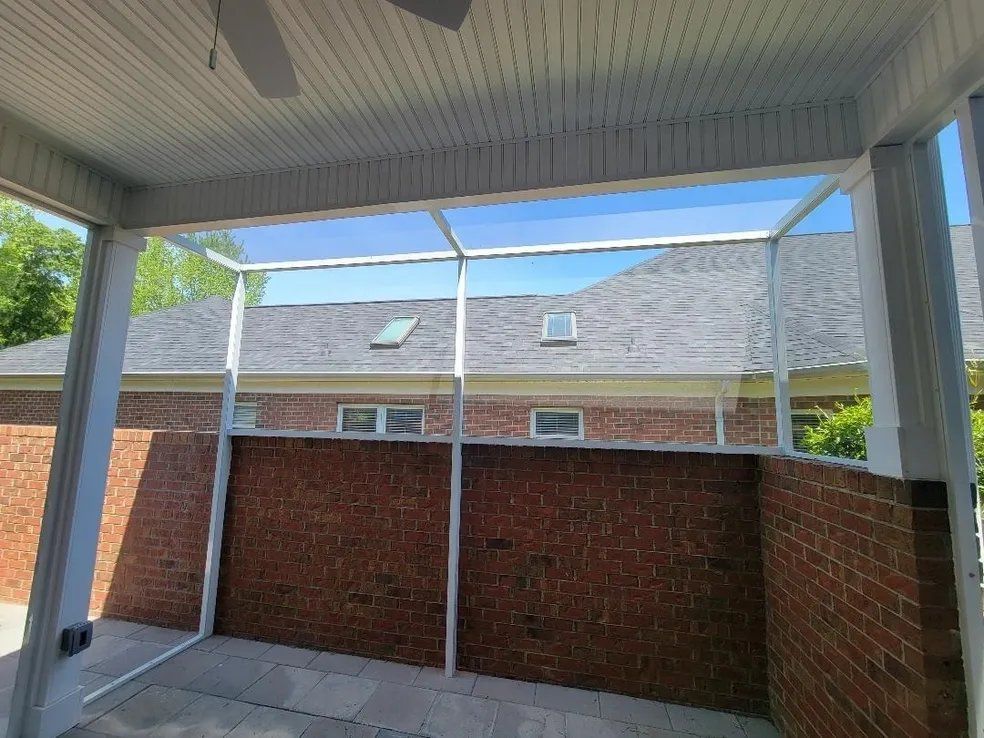 Covered patio with white columns and brick half-walls facing neighboring brick homes