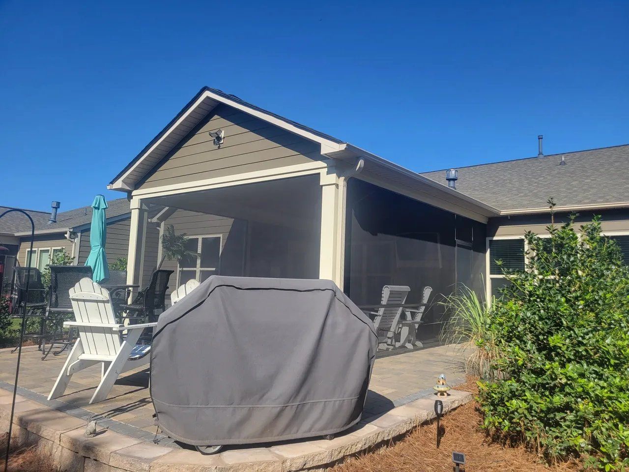 Back patio with covered grill, outdoor furniture, and a screened gazebo under a clear blue sky