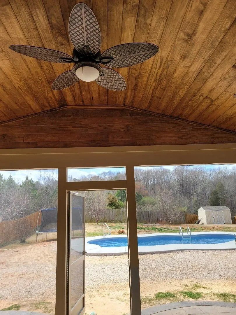 Covered patio with a ceiling fan overlooking a backyard pool and open landscape