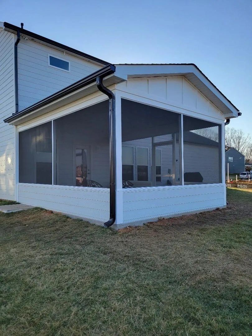 White house exterior with screened porch and dark trim on a grassy lot