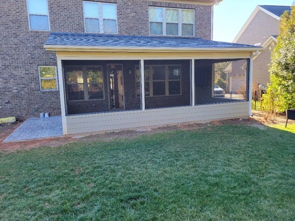 Brick house back porch with screened windows and a grassy backyard