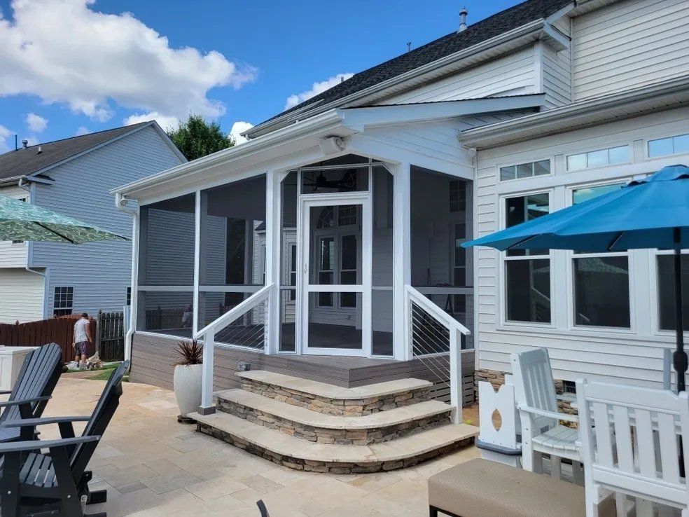 White beach house porch with steps, white railing, and blue patio umbrella on a sunny day