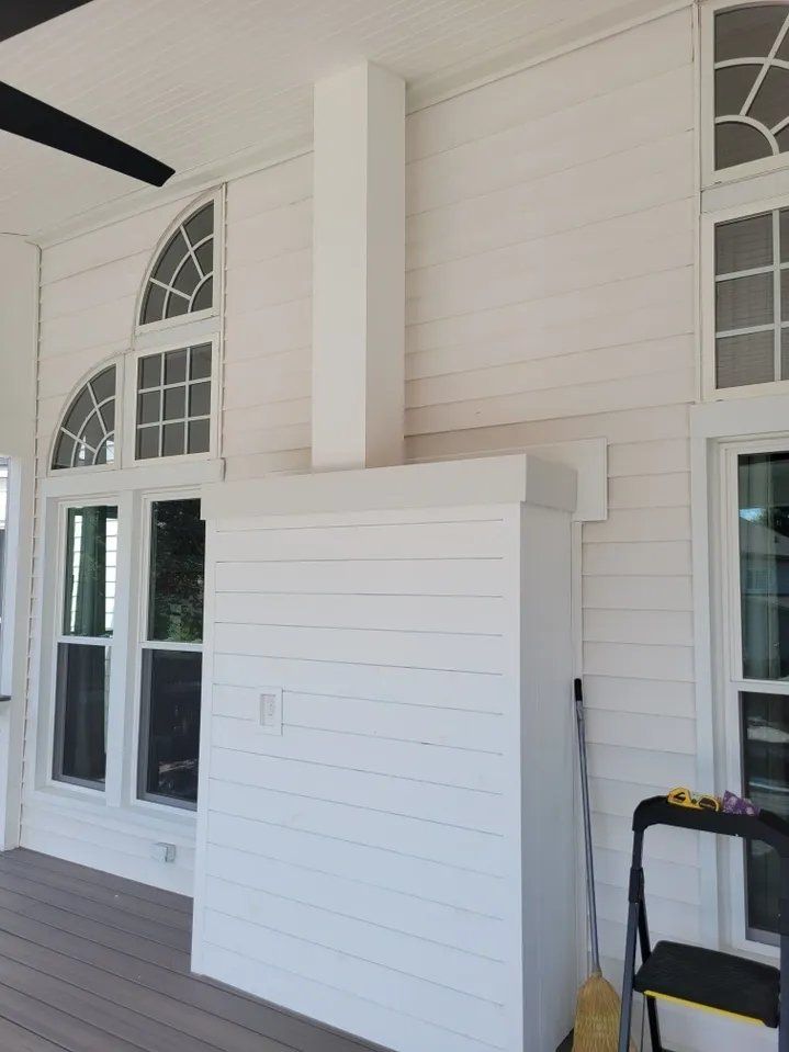 White porch wall with a narrow cabinet-like panel and arched windows on a covered exterior deck