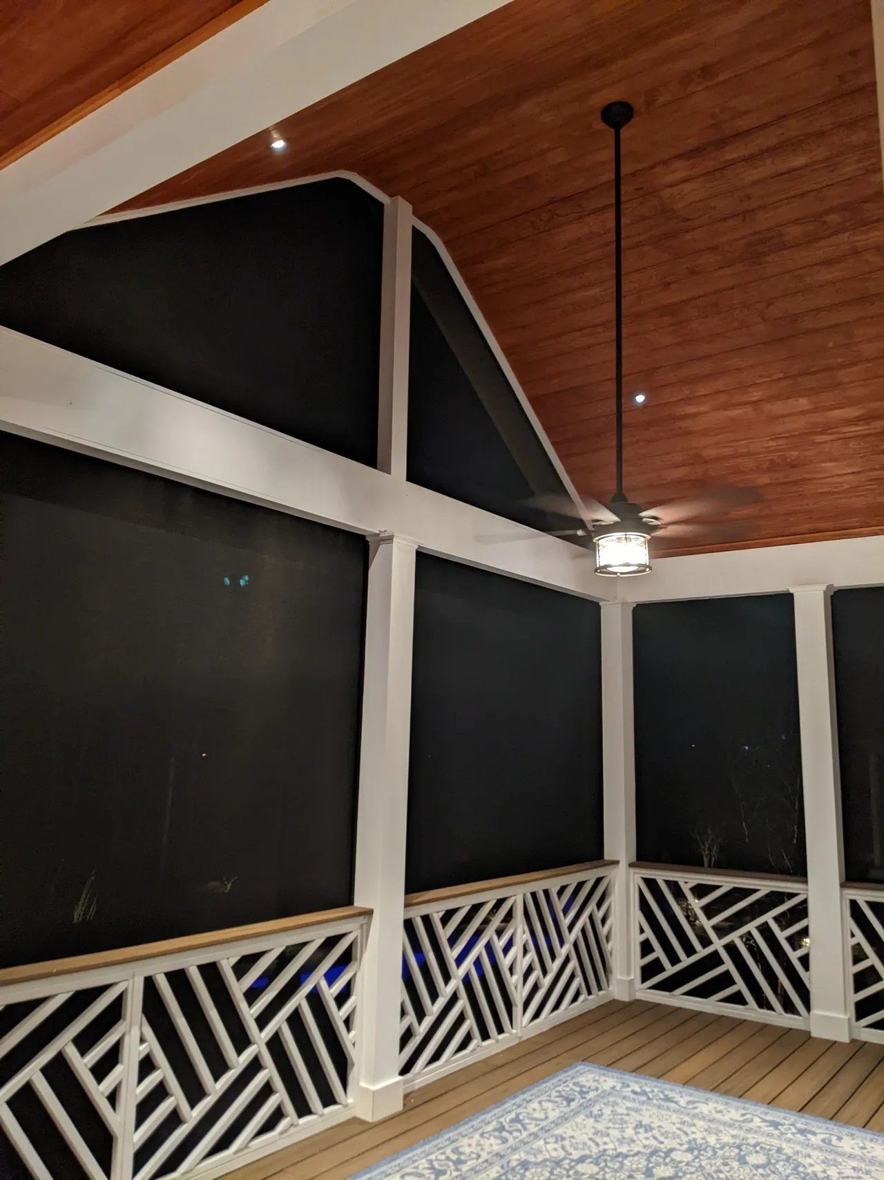 Covered porch with black screens, white railing, wood ceiling, and a hanging light fixture