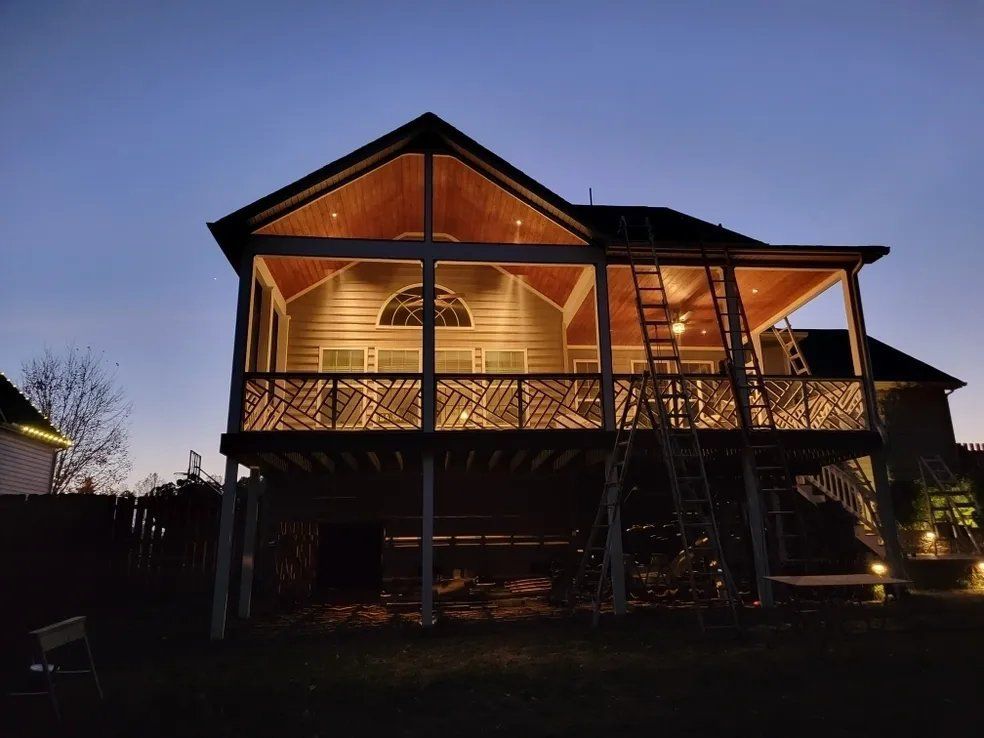 Two-story wooden house with warm lights glowing on the porch at dusk