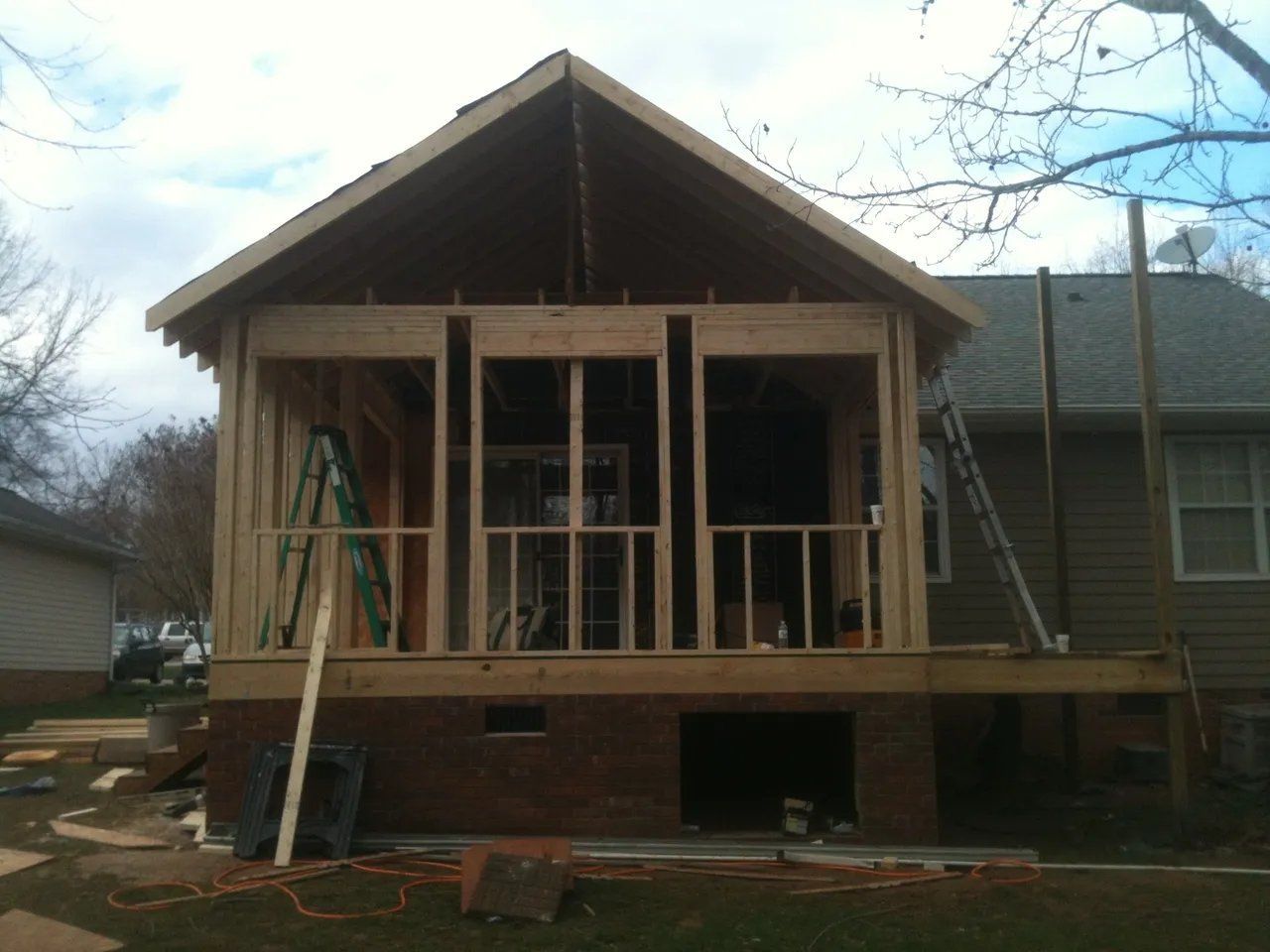 House under construction with exposed wooden framing and front porch