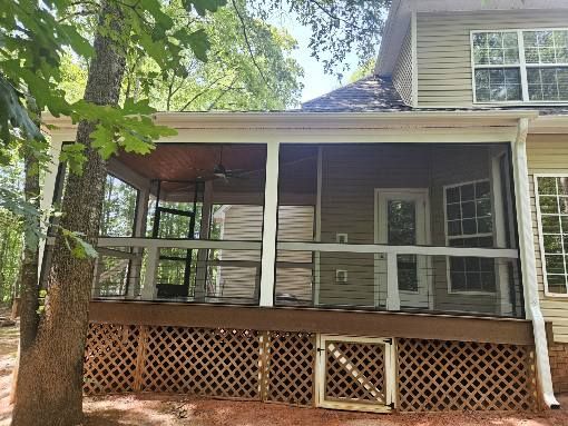 Covered wooden porch with screened railings and lattice skirting on a house exterior