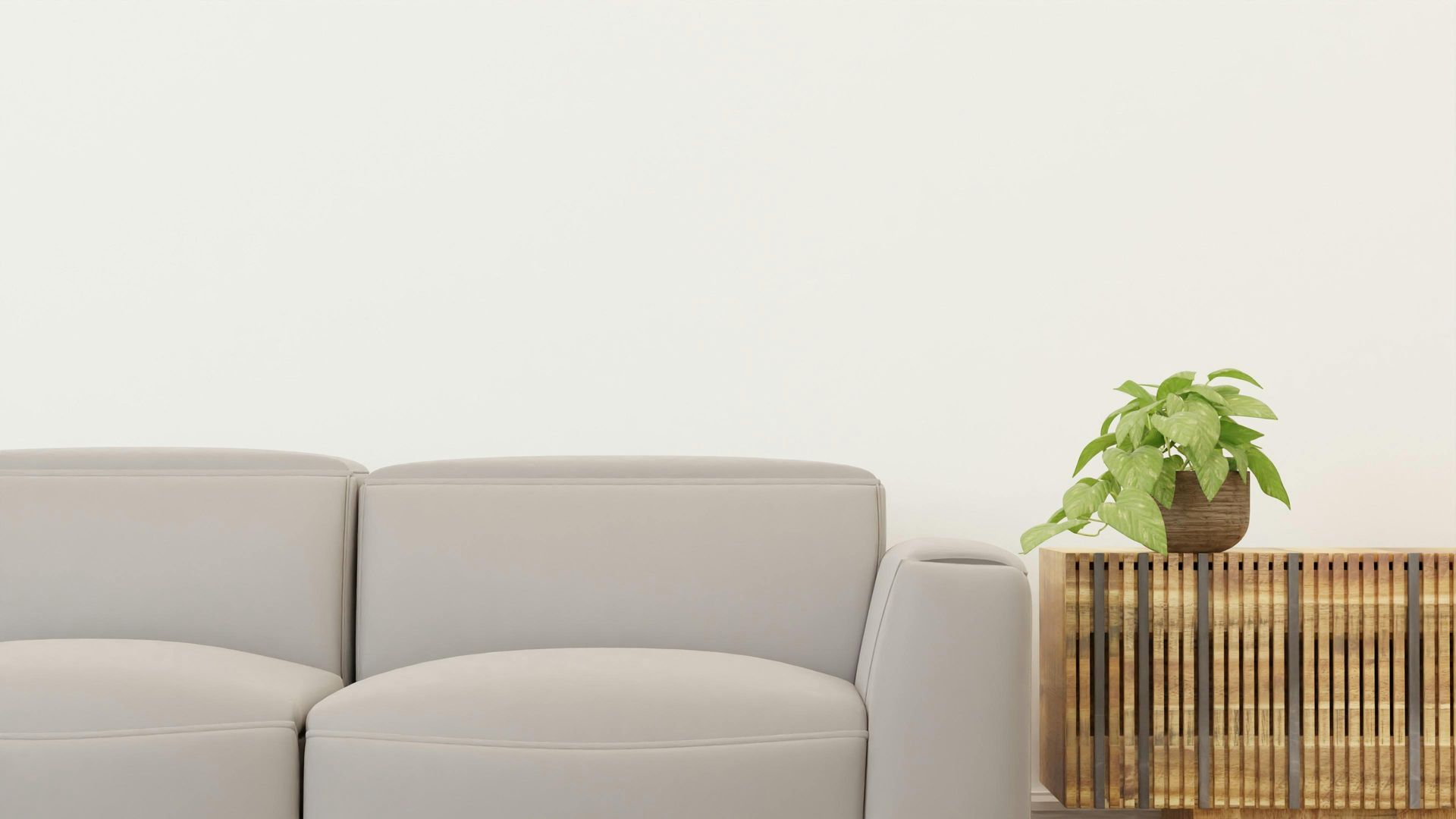 Gray sofa next to a decorative wooden cabinet with a potted plant against a white wall.