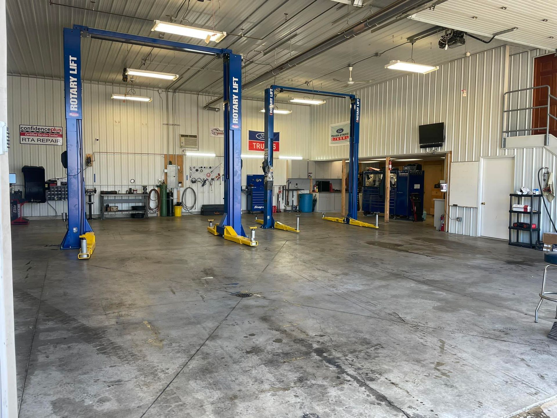 A mechanic shop interior with three vehicle lifts. The concrete floor is visible. The walls are white | RTA Repair