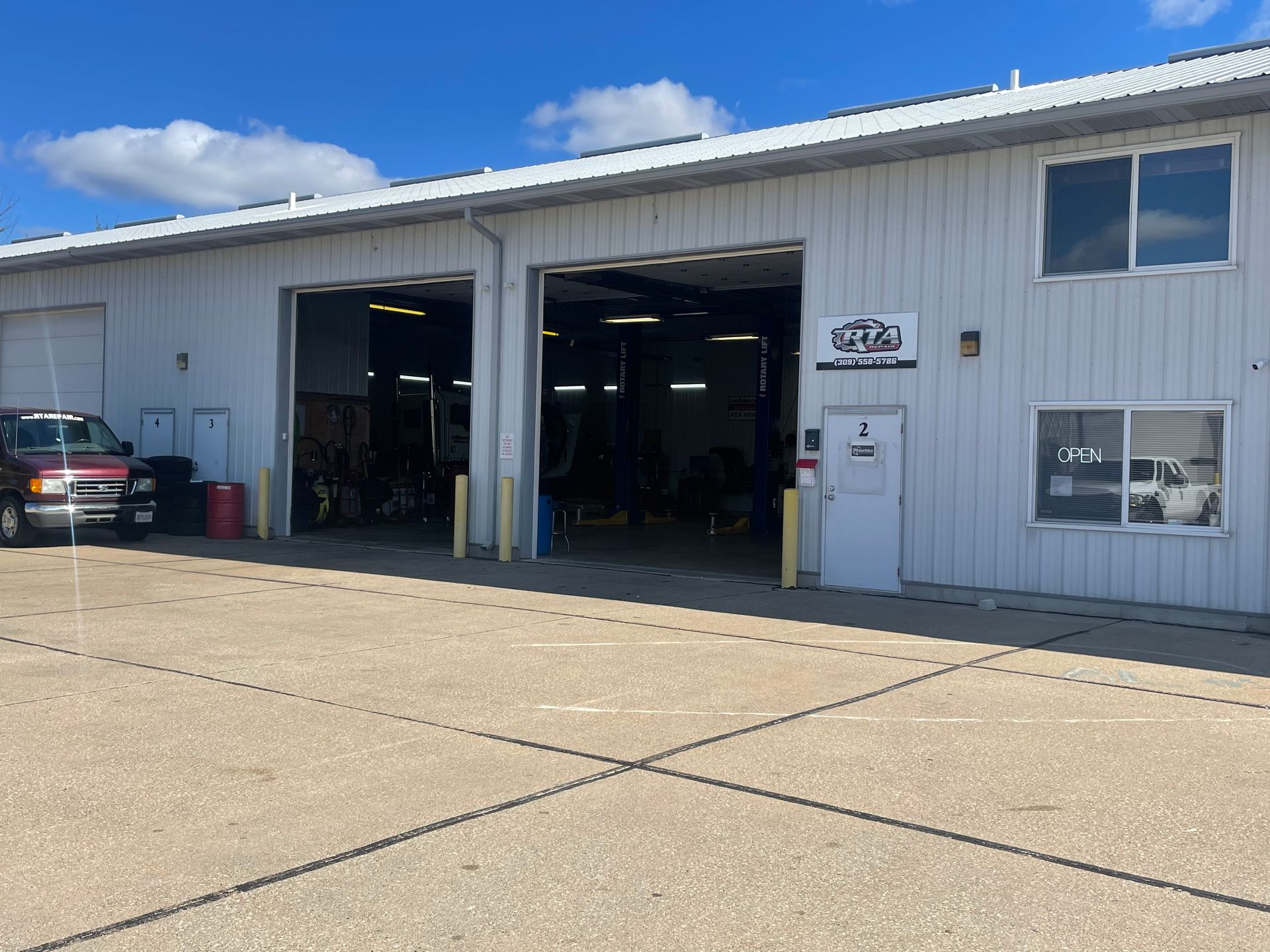Exterior of a mechanic shop with open garage doors; a vehicle is parked outside | RTA Repair