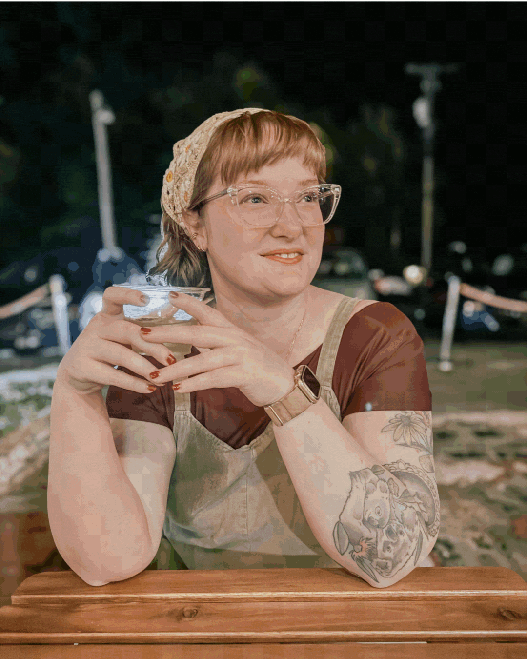 A woman wearing glasses and earrings is sitting in a car.