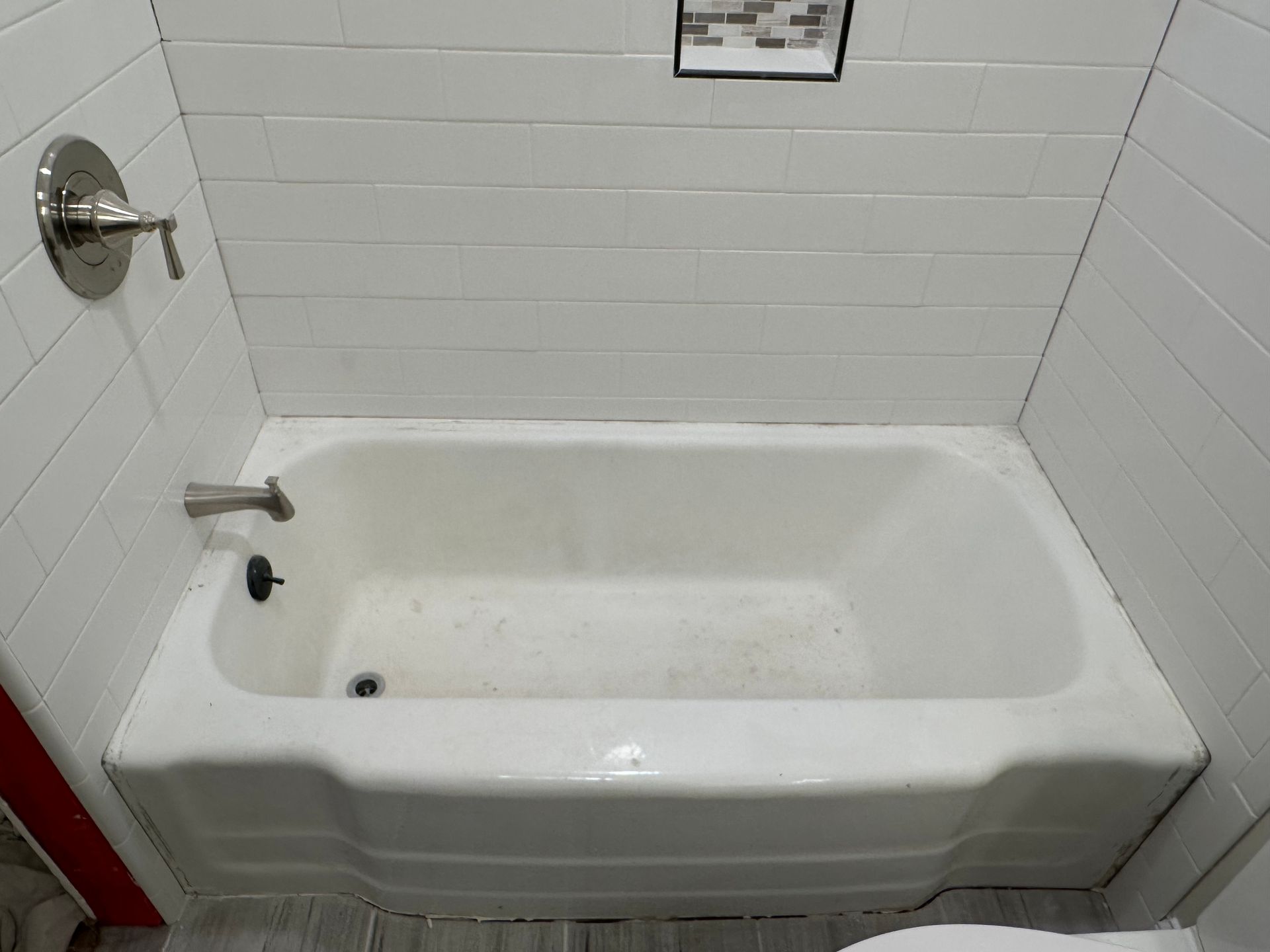A white bathtub in a bathroom next to a toilet.