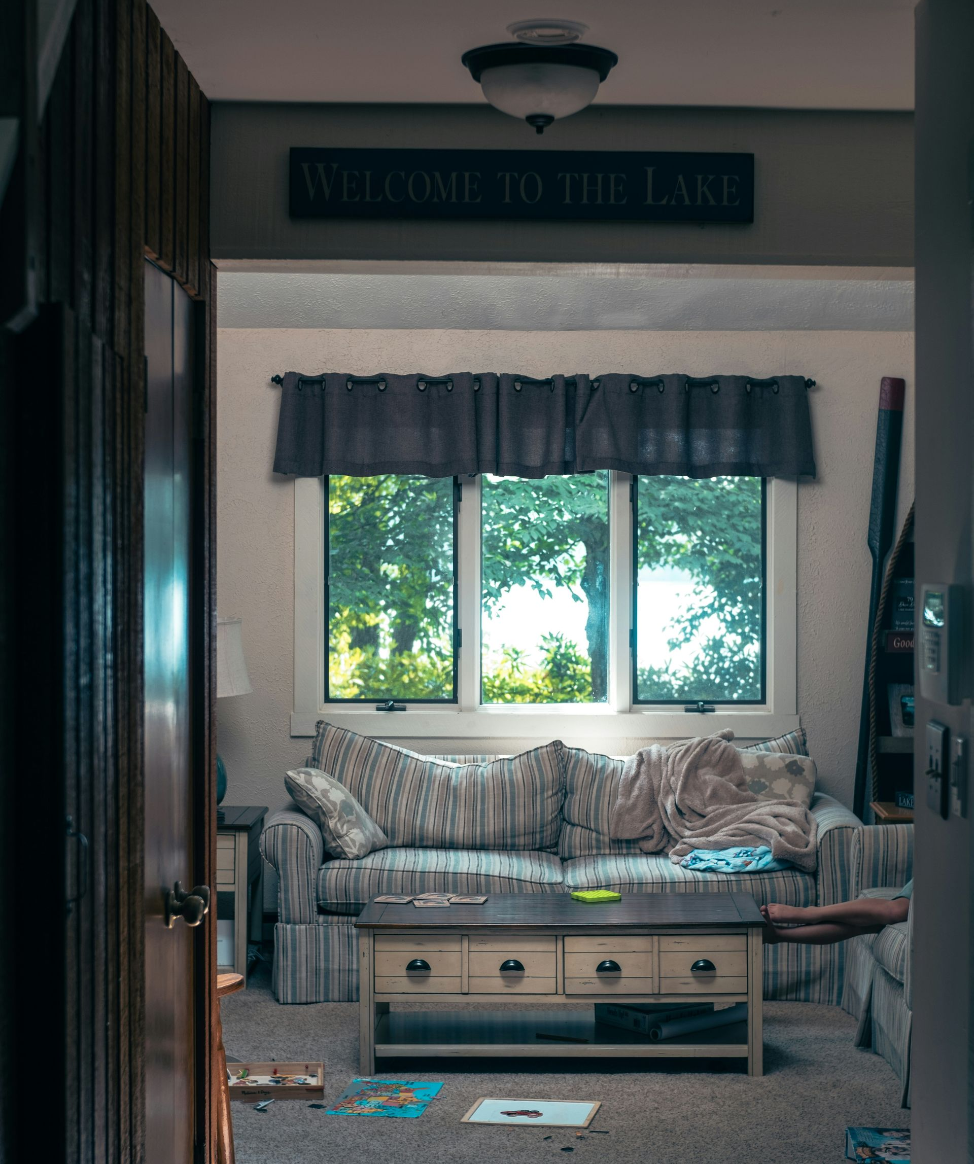 Living room with a couch, coffee table, and window overlooking trees and water. 