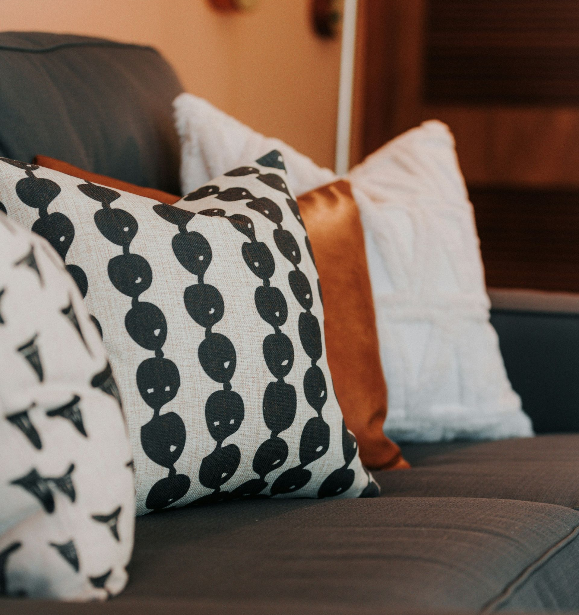 Dark gray sofa with patterned and white throw pillows in a warm-toned living room