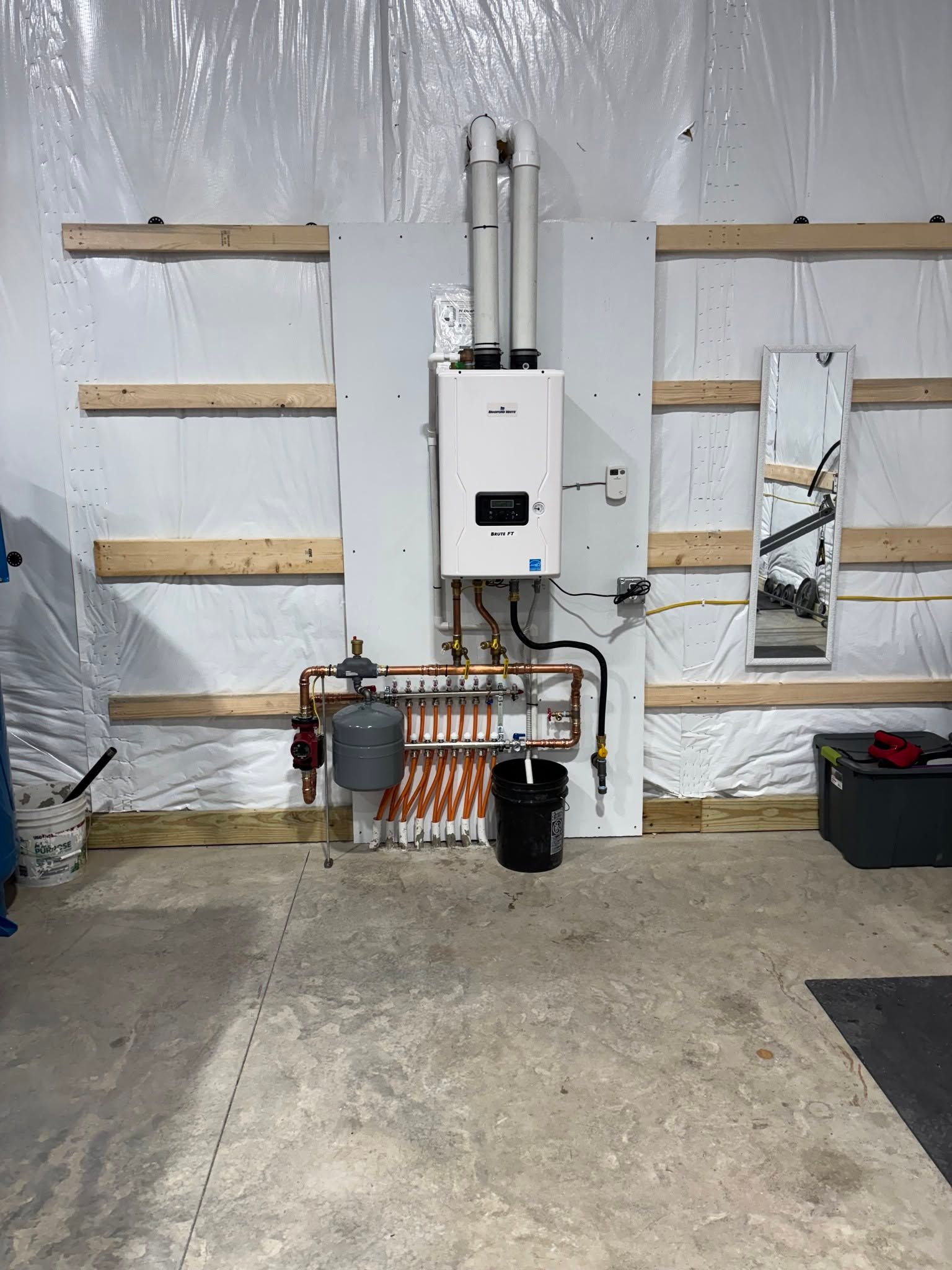 Mechanical equipment mounted on a wall in a utility room, with pipes, shelves, and a concrete floor.