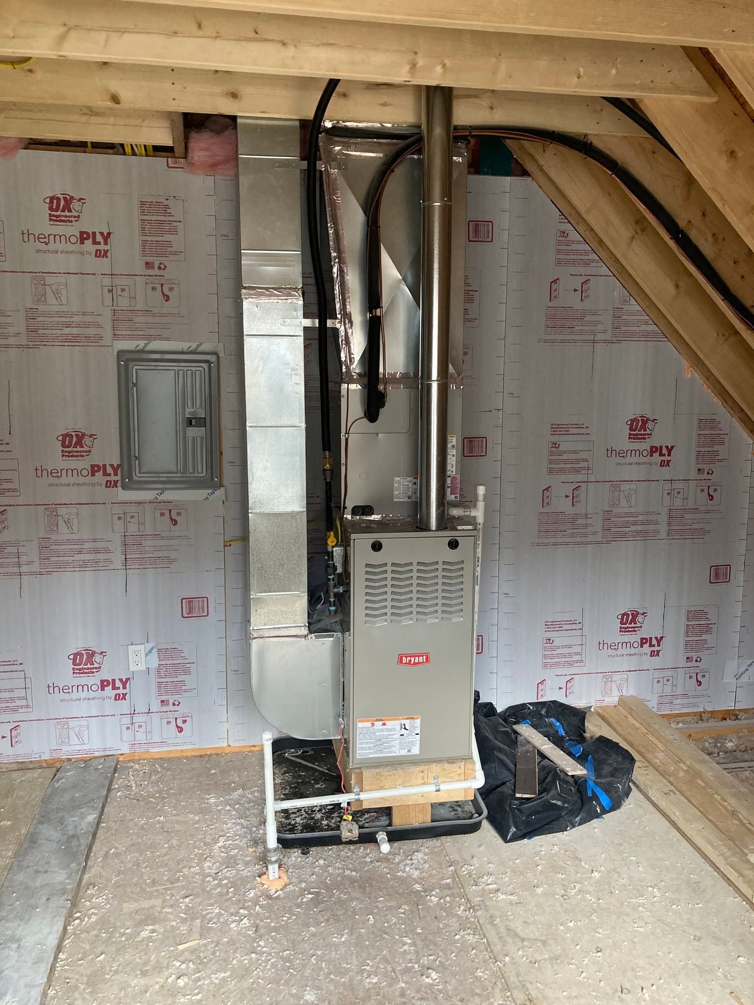 Basement utility room with furnace, ductwork, and insulation under unfinished wooden beams.