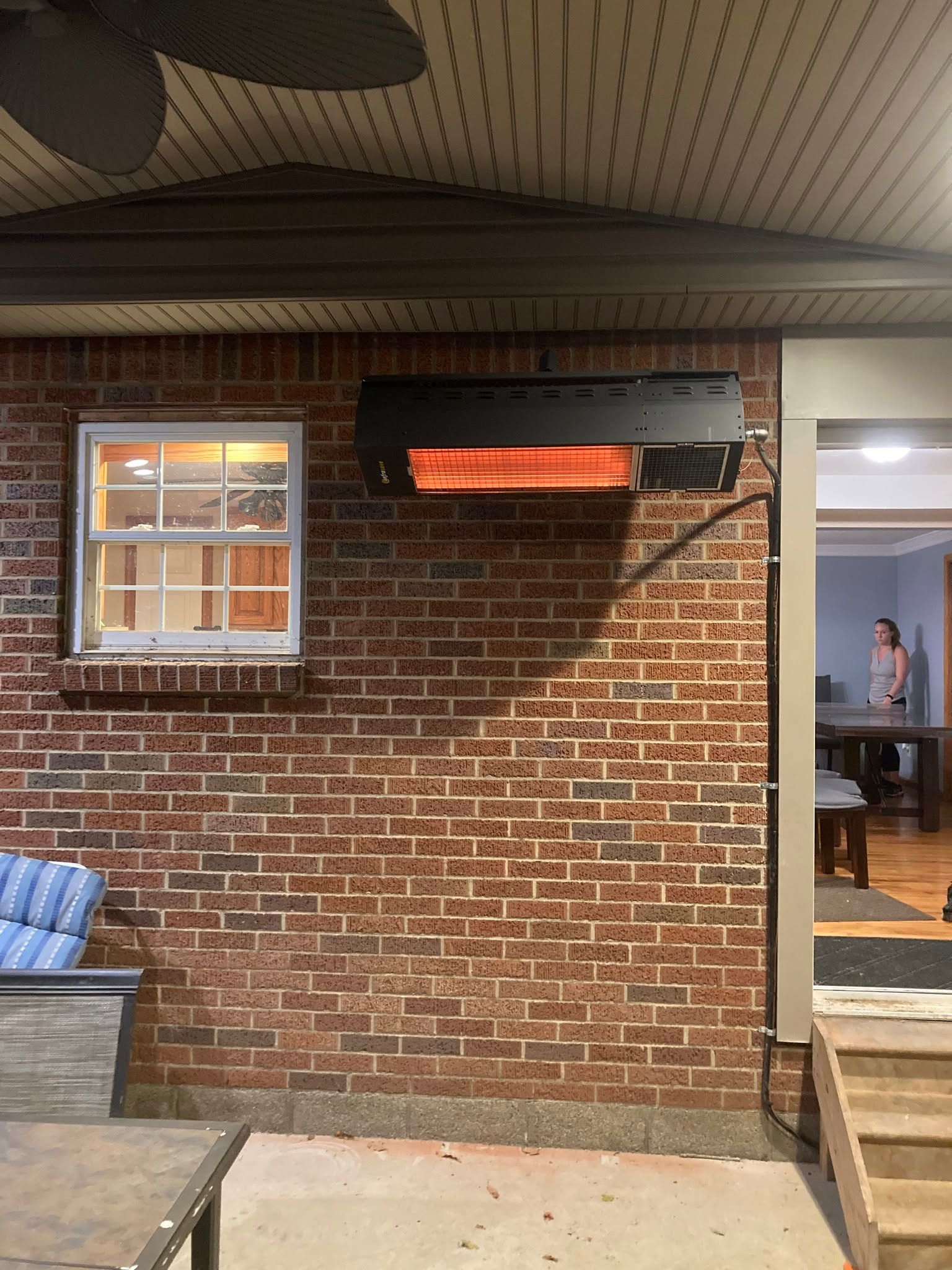 Brick patio wall with a mounted orange heater, window, and open doorway to an indoor room