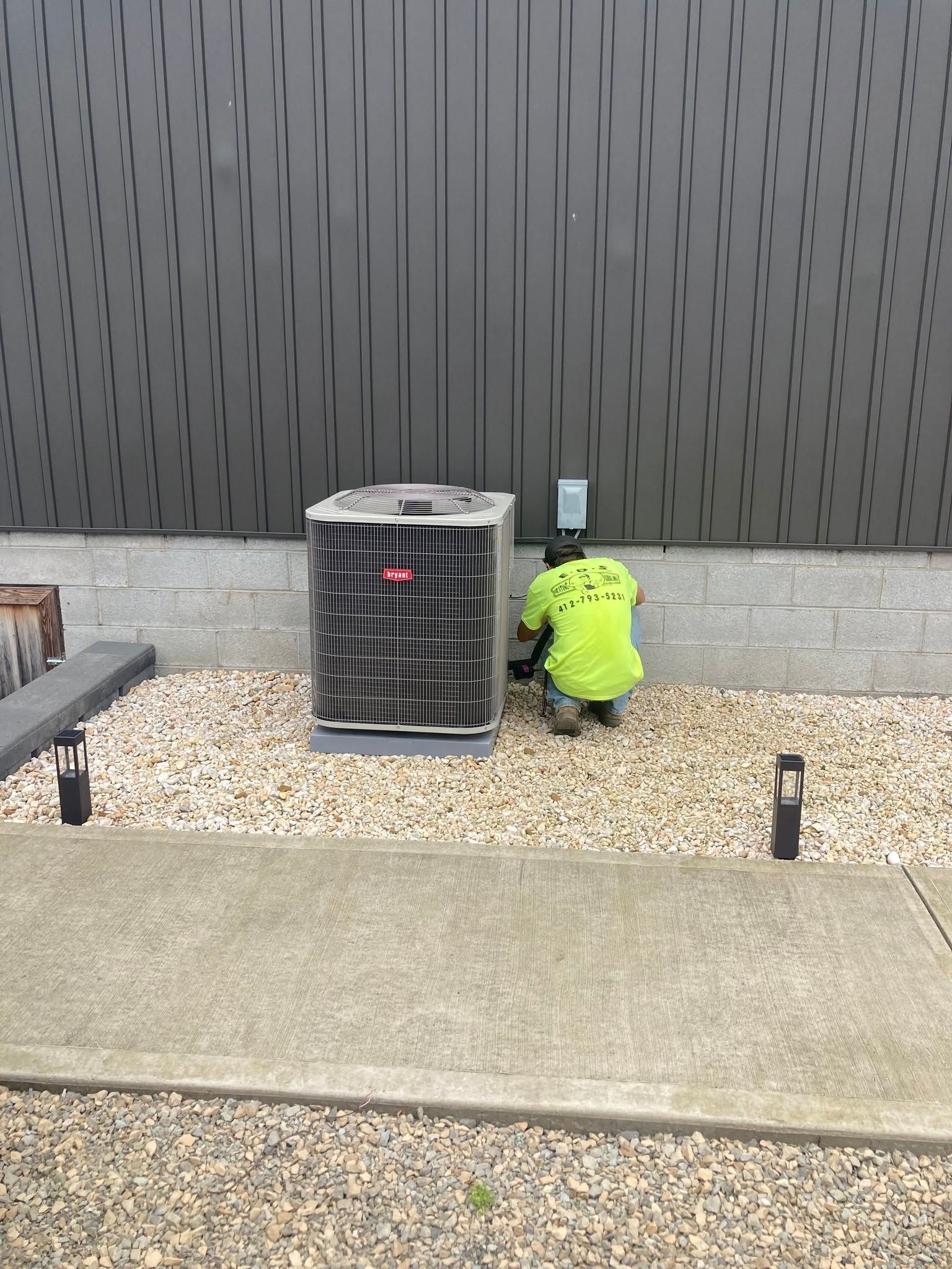 Neon yellow jacket placed beside an outdoor HVAC unit against a dark wall