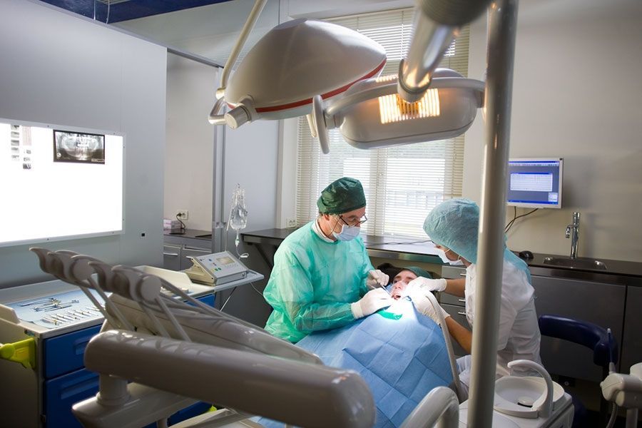 Un dentista sta operando un paziente in sala operatoria.