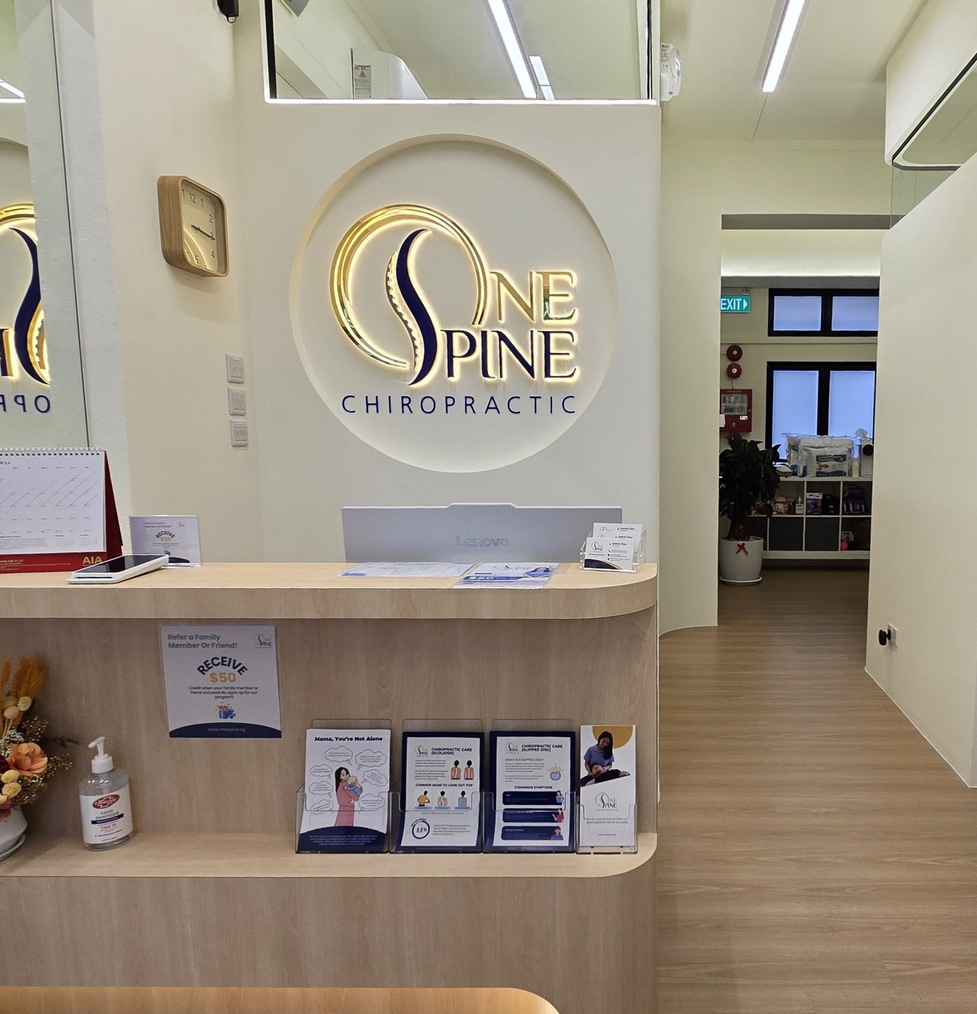 Spine Chiropractic reception desk with logo, brochures, and hallway in a bright clinic lobby