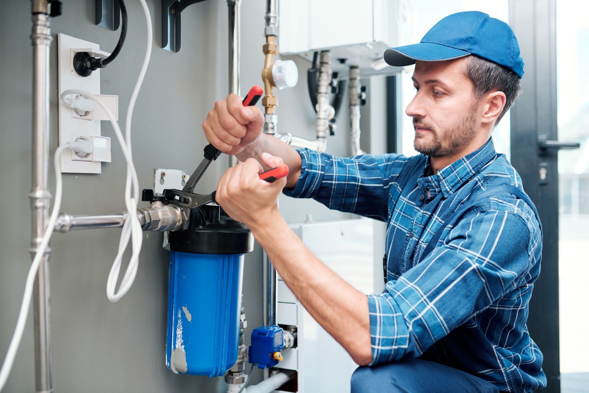 Young plumber installing or repairing water treatment system