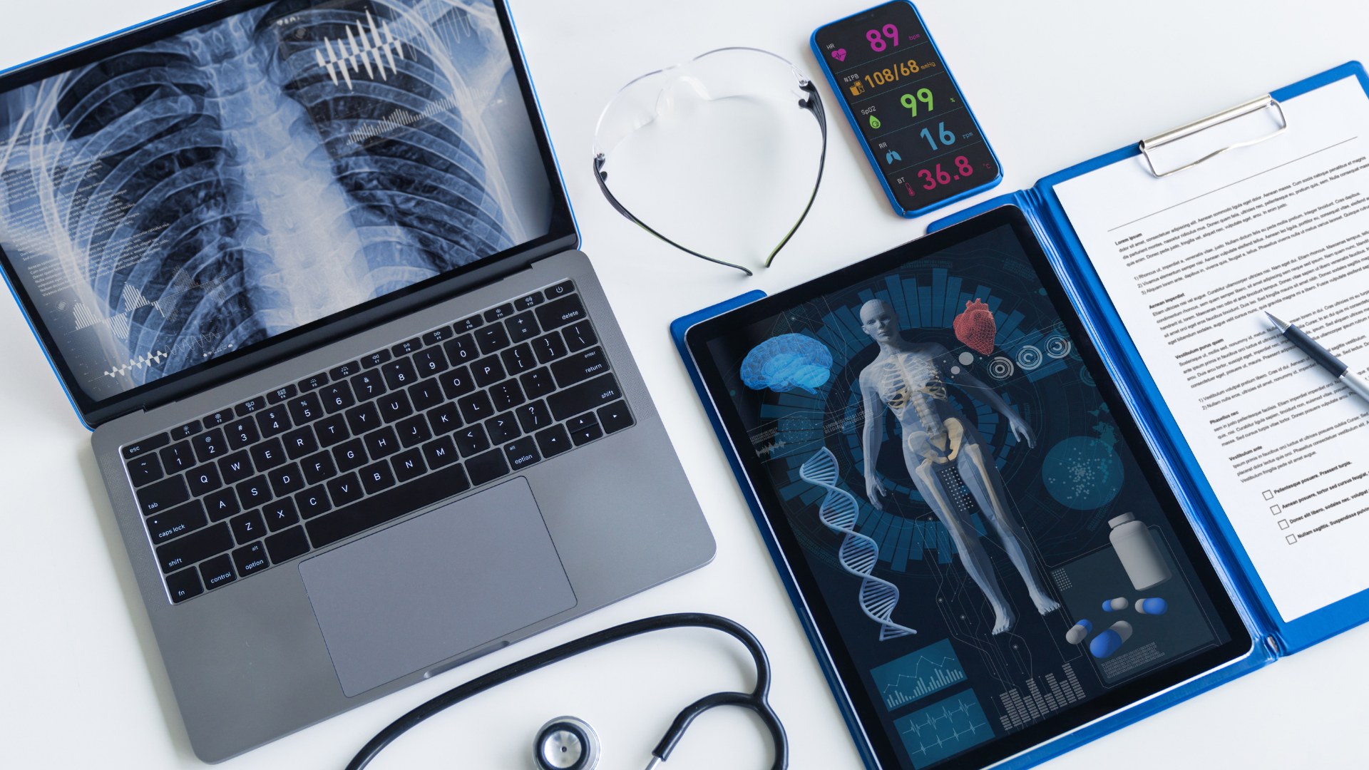 Laptop displaying chest X-ray beside a tablet with full-body scan and medical reports on a white desk