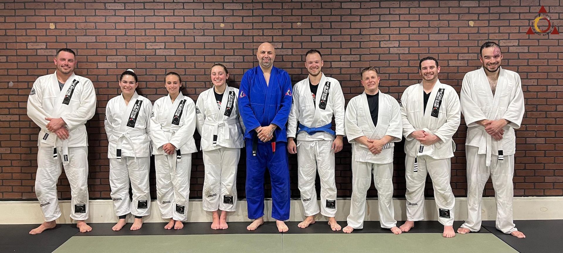 A group of people in karate uniforms are posing for a picture in front of a brick wall.