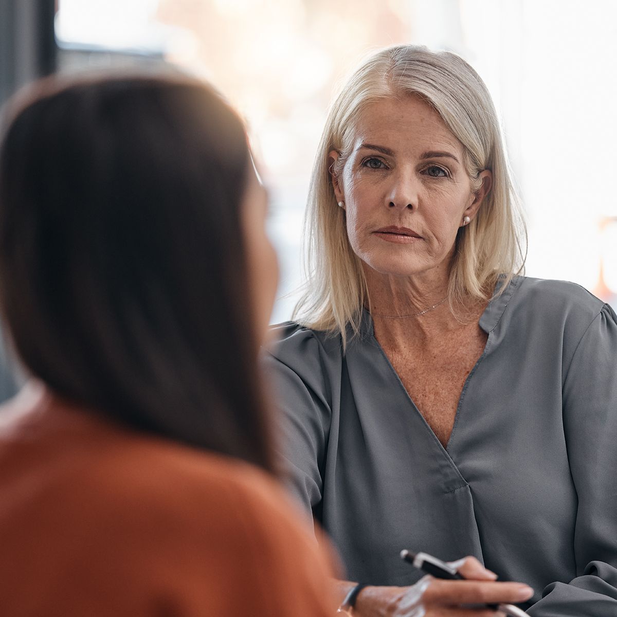 A woman is sitting at a table talking to another woman.