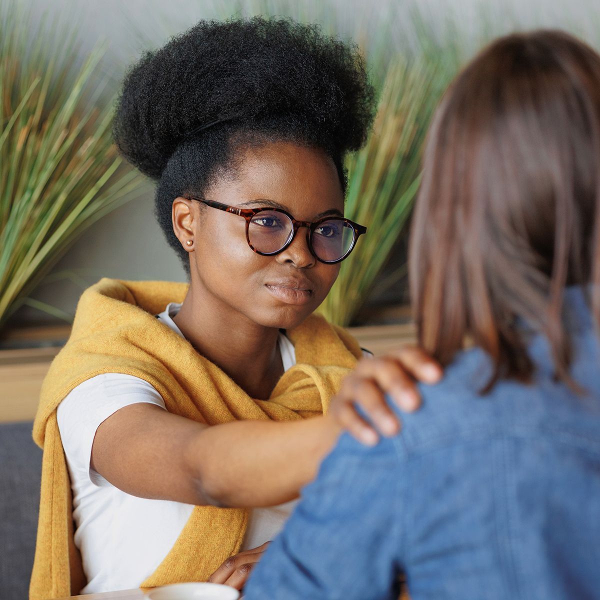 A woman wearing glasses is talking to another woman