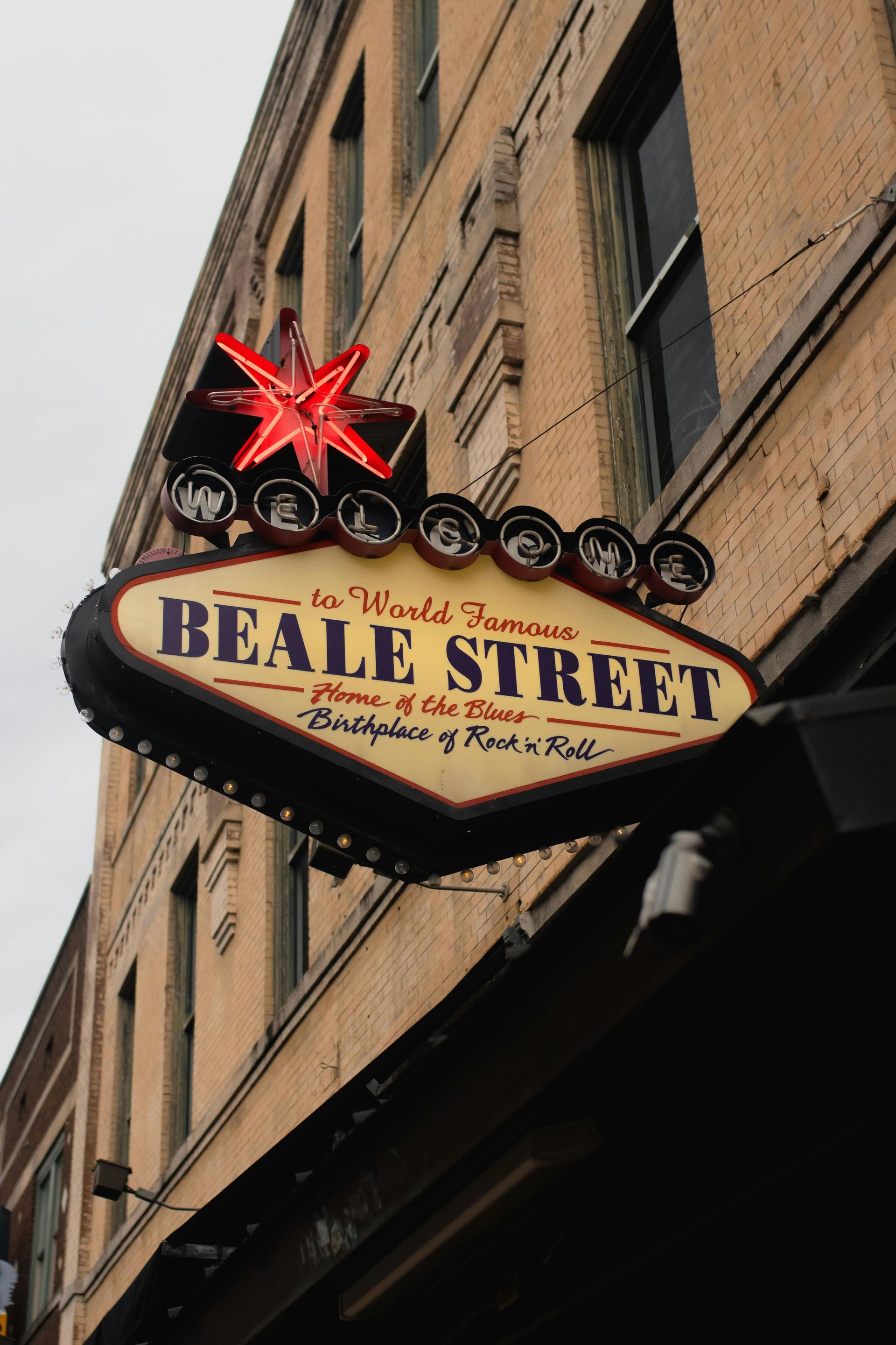 Neon Beale Street sign with red star on a brick building in Memphis.