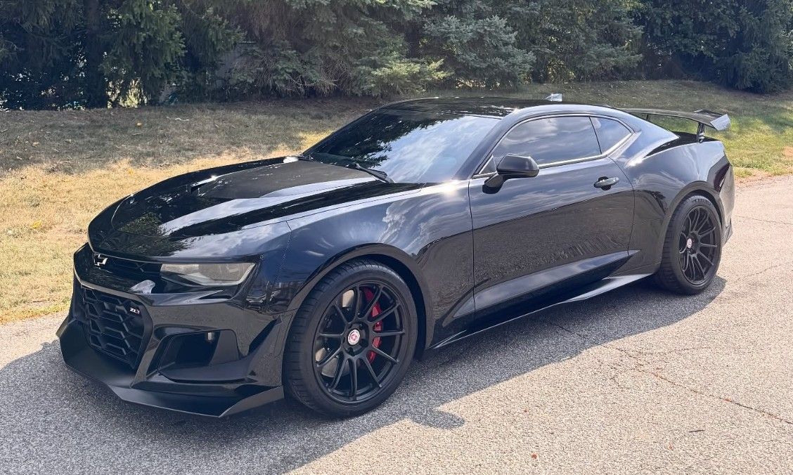 Black Chevrolet Camaro with modifications parked on asphalt.