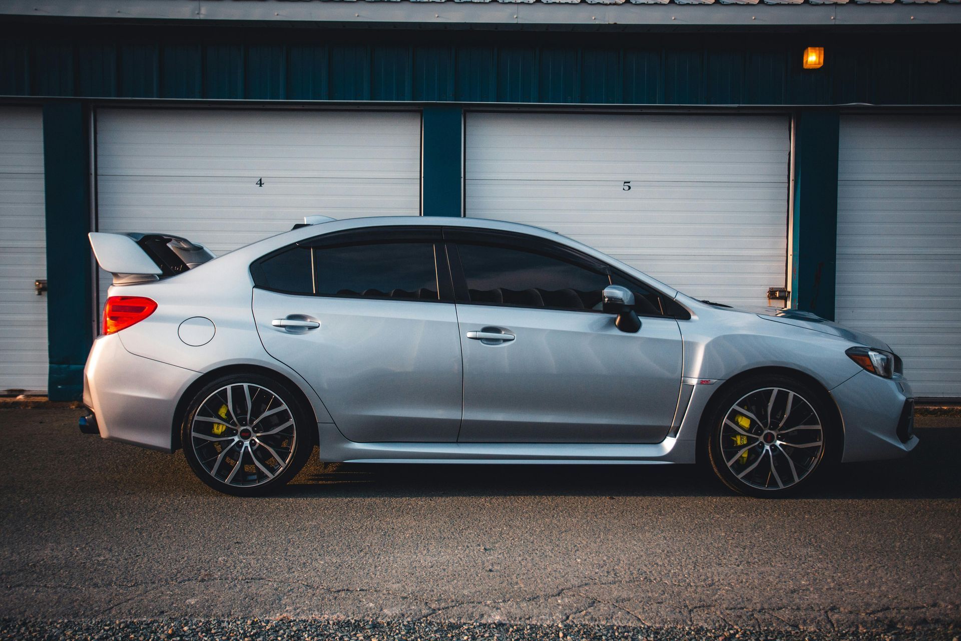 A silver Subaru WRX STI sedan parked in profile outside a storage facility.