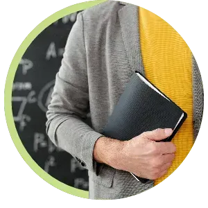 Person in gray sweater holding a black notebook in front of a chalkboard