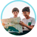 Two children smiling and looking at a map inside a light blue circle
