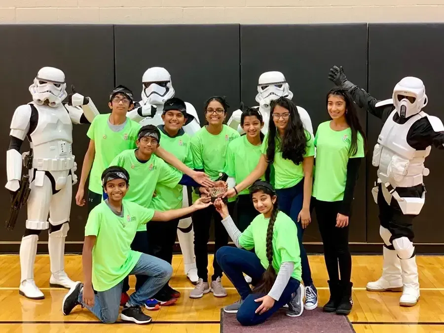 Group in bright green shirts posing with Star Wars stormtroopers on a gym floor