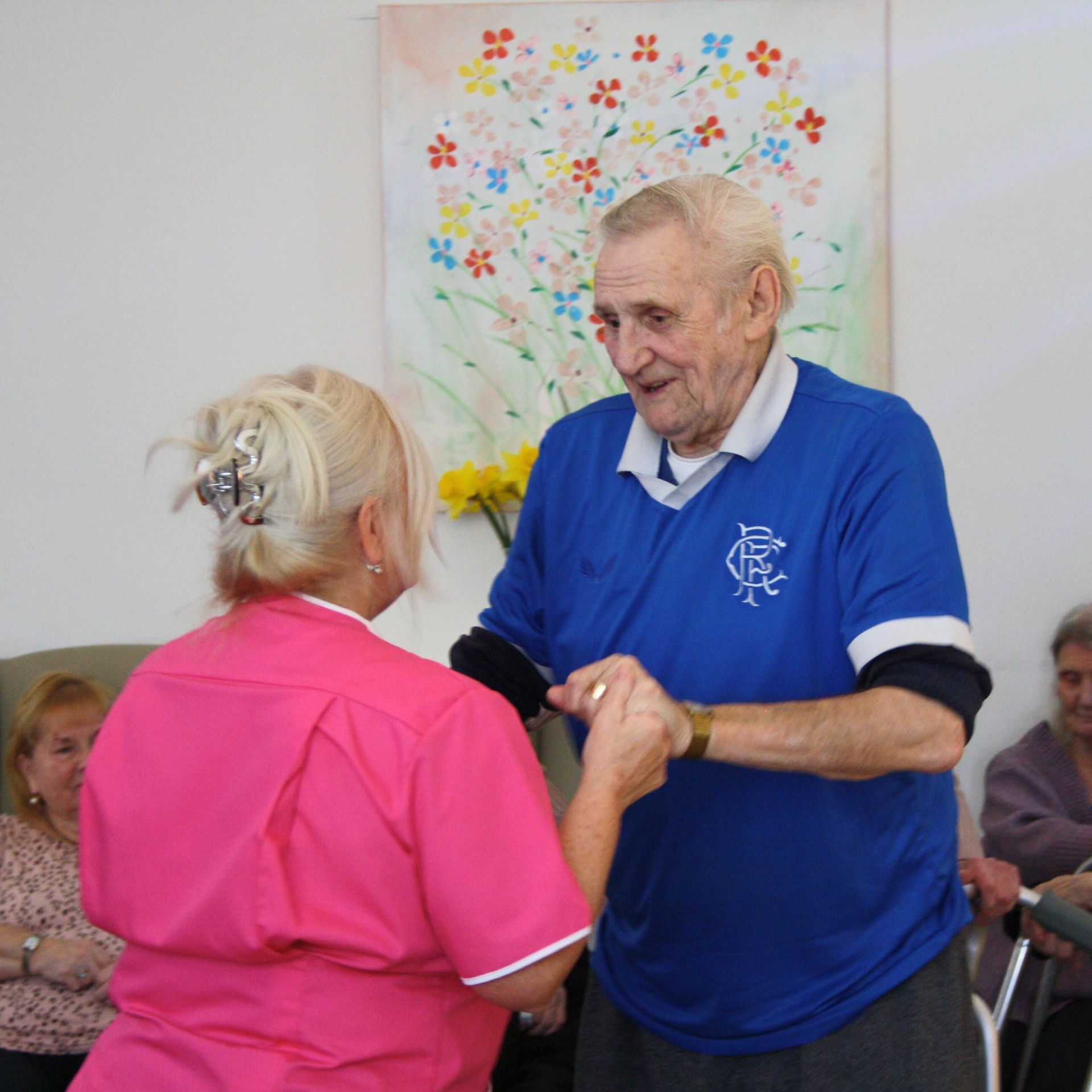 A man in a blue shirt is dancing with a woman in a pink shirt