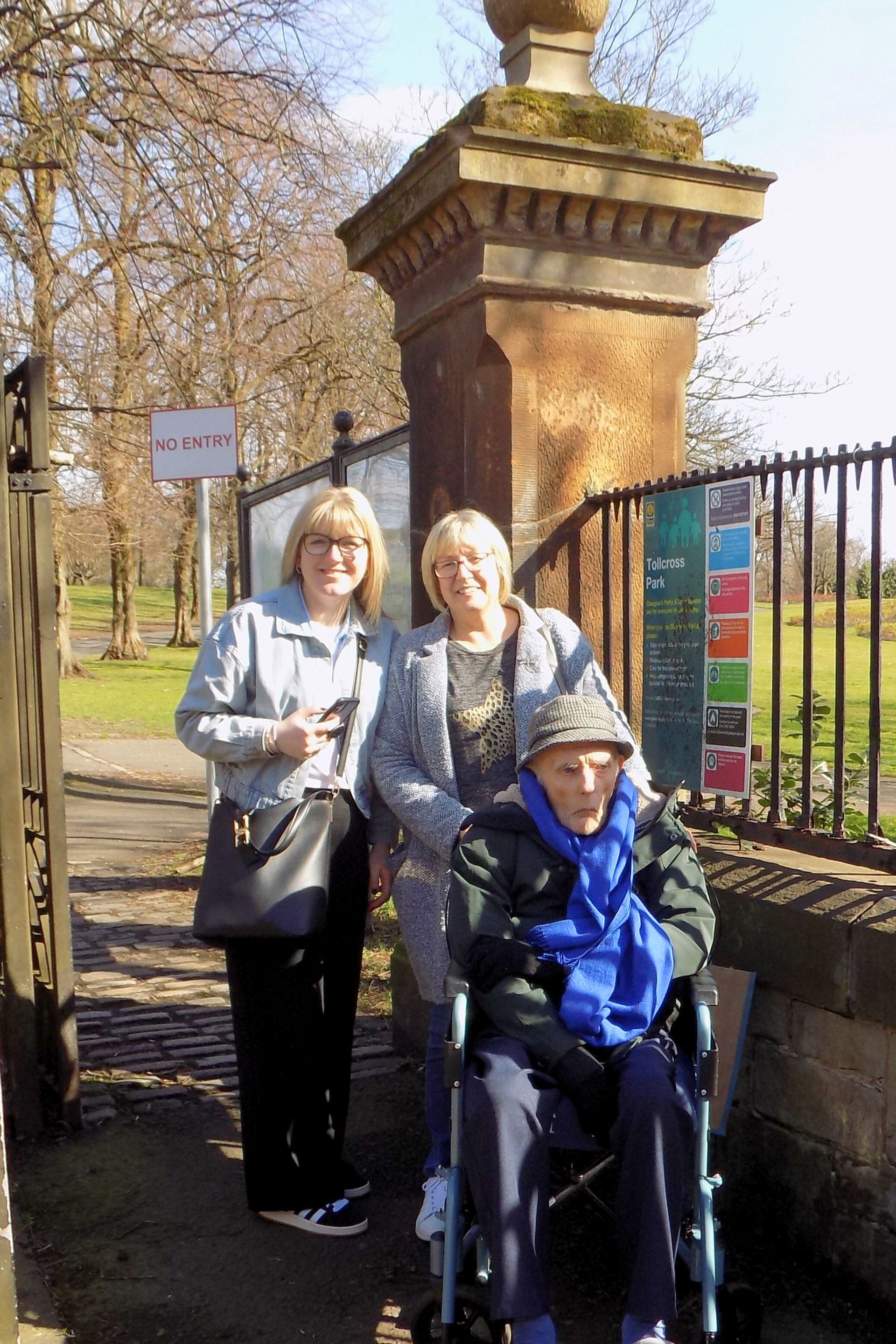 A man in a wheelchair is sitting next to two women.