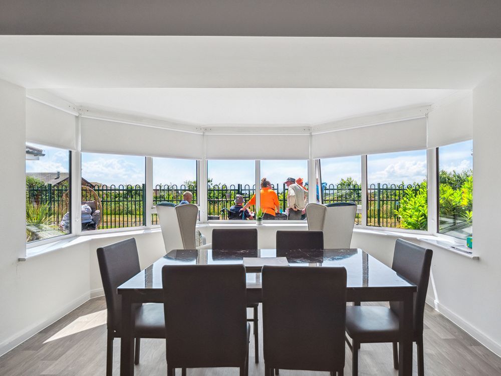 A dining room with a table and chairs and a large window at Arran View