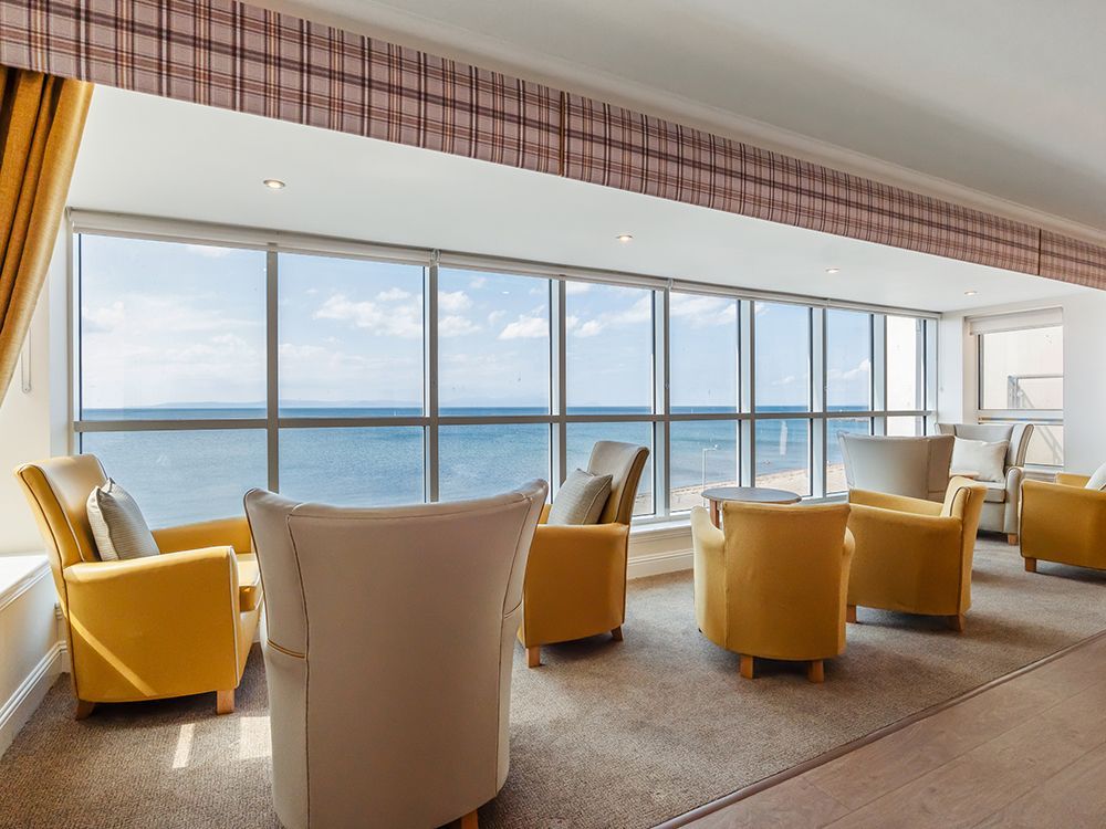 A living room with yellow chairs and a view of the ocean
