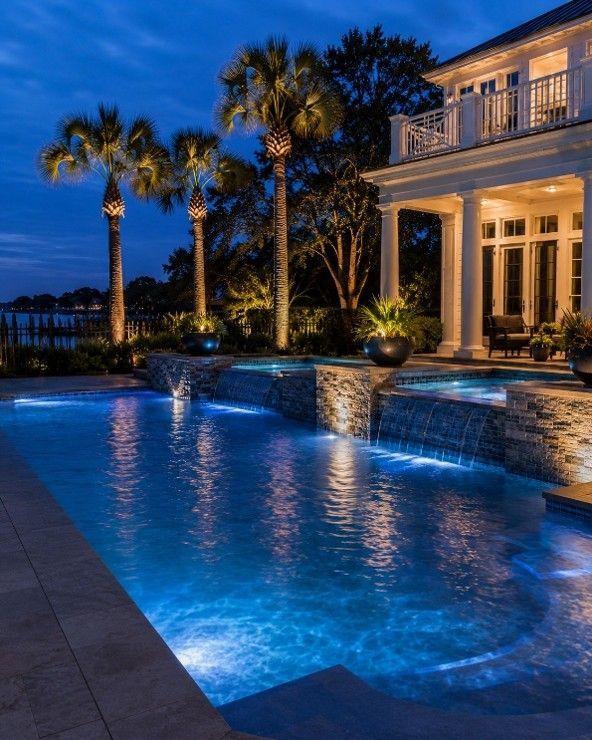 Renovated pool with lit waterfalls and palm trees at a Mount Pleasant, SC waterfront home